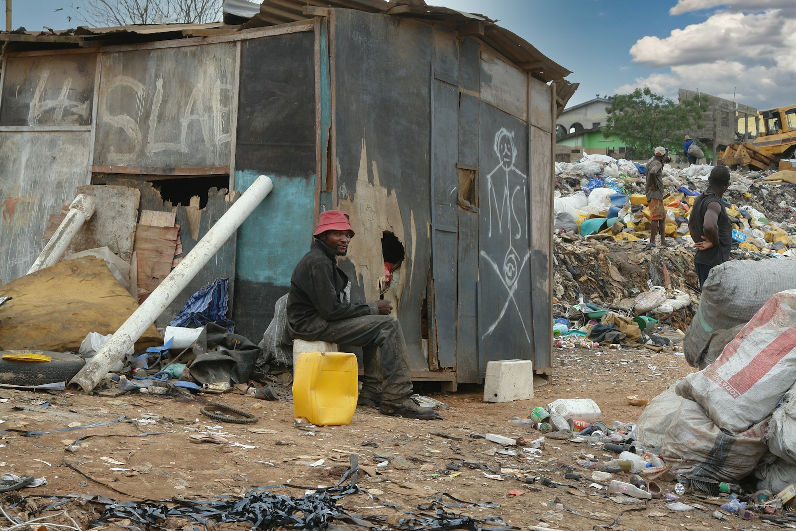 man in black jacket sitting on ground near garbage